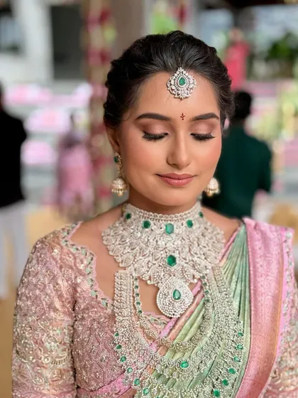 A close-up of Manasa's makeup, with soft pink tones on the eyes and a flawless base that lets her diamond and emerald jewelry take center stage.