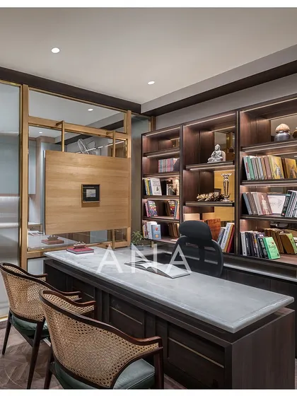 This managing director's cabin was custom-designed to feel luxurious yet minimal. The space features a Michelangelo stone top desk, a book cabinet with a brown mirror back, and glass partitions framed in MS with veneer cladding for a sophisticated corporate interior.