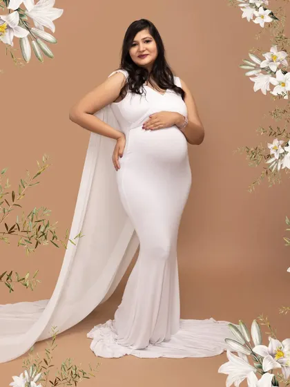 The definition of elegance. This mother-to-be is wearing a beautiful white cape gown from my studio collection, creating a classic and graceful silhouette against a simple backdrop.