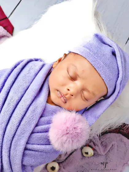 A close-up on the baby's face and the adorable pom-pom detail on his hat.