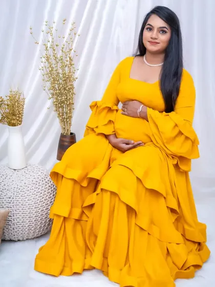 A radiant mother-to-be in our vibrant yellow tiered maternity gown. The ruffled sleeves add a touch of playfulness.
