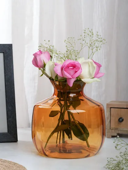 An amber glass vase with pink and white roses, shot in natural light. The soft, romantic lighting is perfect for showcasing delicate home decor items.