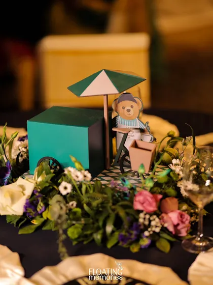 Our table centerpieces were miniature works of art. This one features a tiny teddy bear with its own popsicle cart, nestled in a bed of fresh flowers, adding a touch of whimsy and intricate detail to the first birthday party decor.