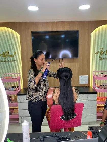 A trainer uses hairspray to set a style, a fundamental technique for ensuring a long-lasting hairdo.