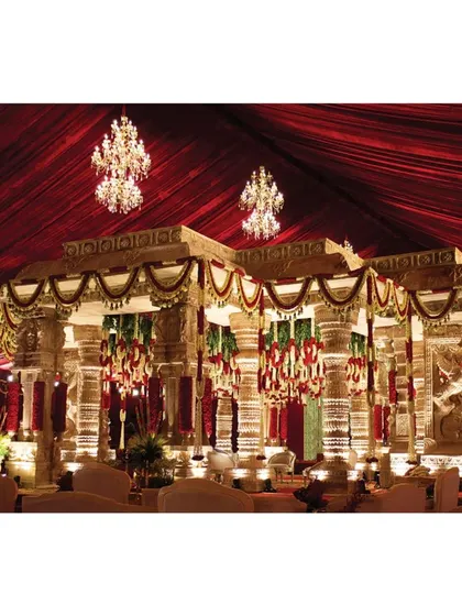 This image captures the mandap as a sacred space where tradition meets contemporary luxury. The combination of ancient architectural forms, opulent floral decor, and modern lighting creates a perfect setting for a grand Indian wedding.
