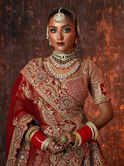 A mid-shot capturing the traditional styling, from the layered necklaces to the vibrant red bangles, on a model with a beautiful deep skin tone.