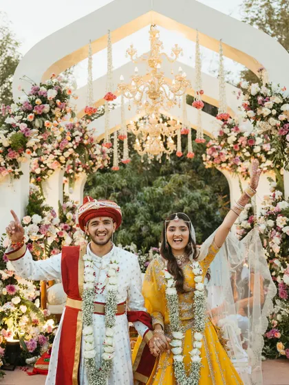 A moment of pure joy as the couple celebrates at their floral-arch mandap. The combination of traditional elements and modern design created a perfect setting for their happy beginning.