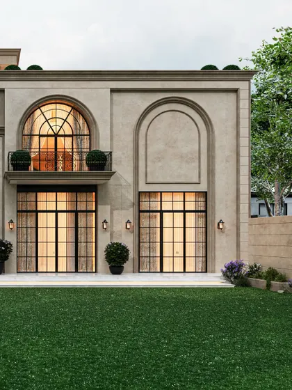 The rear facade of this classical residence uses a rhythm of arched and rectangular openings to create a balanced and stately composition. The design brings a sense of historical grandeur to a modern home, with large windows connecting the interior to the lawn.