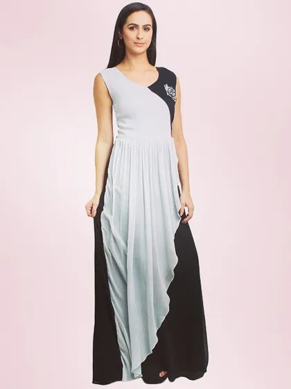 A model in a striking dual-color maxi dress. The design combines black and light grey panels in a draped silhouette, with a small embellished motif on the shoulder for a touch of sparkle.