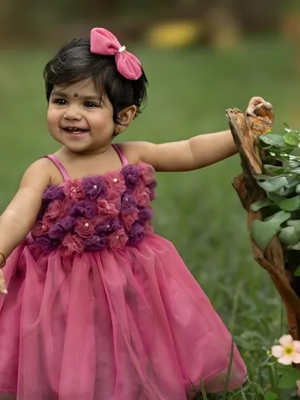 Celebrating a first birthday in a beautiful garden setting. This little girl in her pink party dress is all smiles.