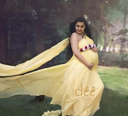 A gentle and serene maternity photo with our yellow trail gown. The soft fabric flows beautifully, adding a touch of elegance to this outdoor shot.