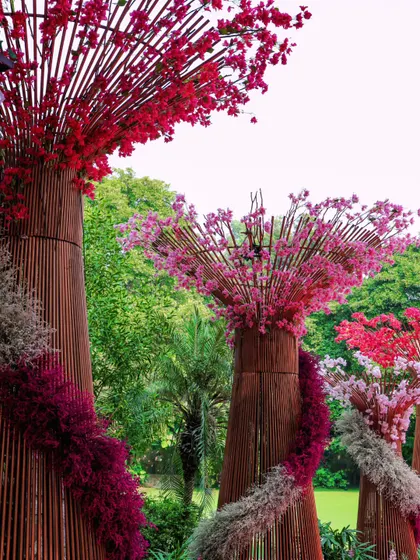 A closer look at the unique floral tree sculptures, crafted with bamboo and vibrant bursts of pink and red flowers, creating a whimsical forest feel.