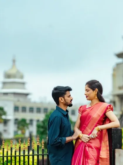 A candid moment between a couple in front of the Vidhana Soudha, capturing a natural interaction and genuine smiles.