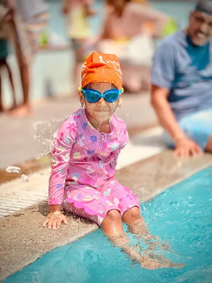 A series of candid shots showing a young swimmer's journey of getting comfortable at the pool's edge. From happy claps to playful splashes, it's all part of the learning process.