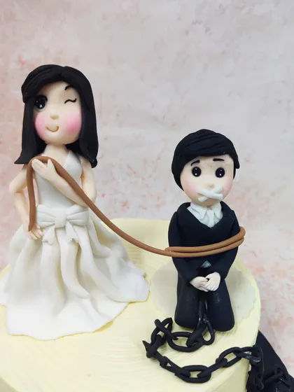 We add a touch of humor to the big day with this cheeky "Game Over" wedding cake. A winking bride holds the groom on a leash, complete with a ball and chain, making for a playful and memorable cake for a couple with a great sense of humor.