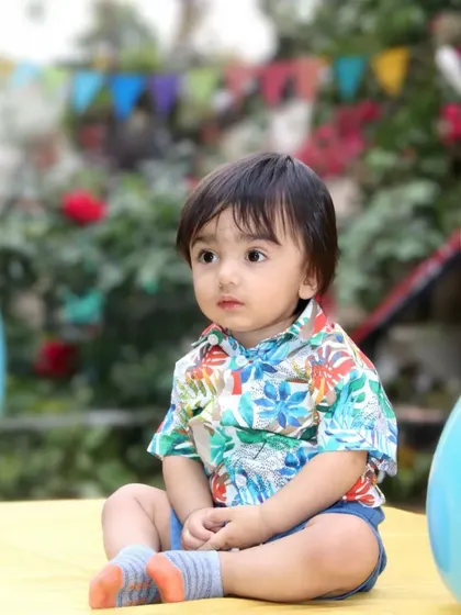An outdoor portrait of a baby boy sitting thoughtfully amidst balloons. I shoot in various locations, including outdoors.