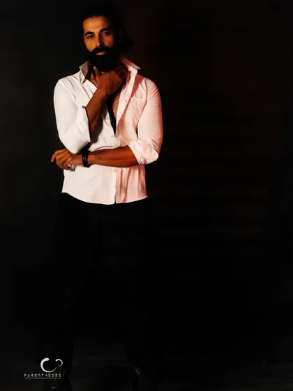 Using negative space to create a dramatic, low-key male portrait. The single light source carves him out of the darkness, emphasizing form and a brooding intensity.