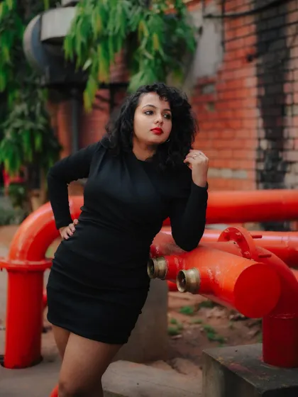 A duplicate of image 474, this portrait uses the contrast of a black dress against red pipes for a striking industrial fashion shot.