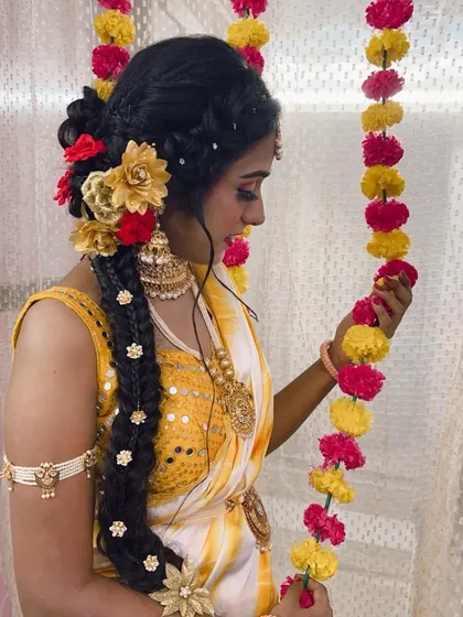 A side view of a long, thick braid decorated with flowers, created for a Haldi ceremony. This style is both traditional and very photogenic.