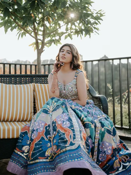 A stunning close-up of the bride at her Mehendi, her colorful lehenga and the beautiful scenery creating a perfect frame. This shot highlights her poise and the beauty of the moment.