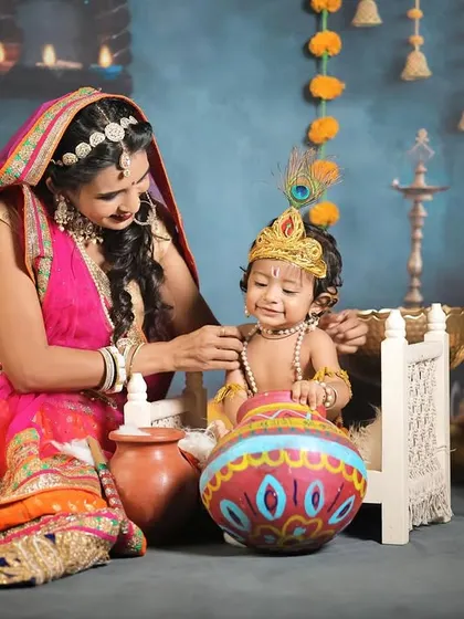 A mother dressed as Yashoda lovingly adjusts her baby Krishna's necklace in this divine-themed shoot.