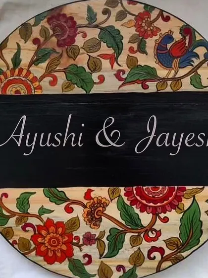 This circular Kalamkari nameplate is a burst of color and tradition. The intricate floral and bird motifs are painted directly onto the wood, making each one slightly different.