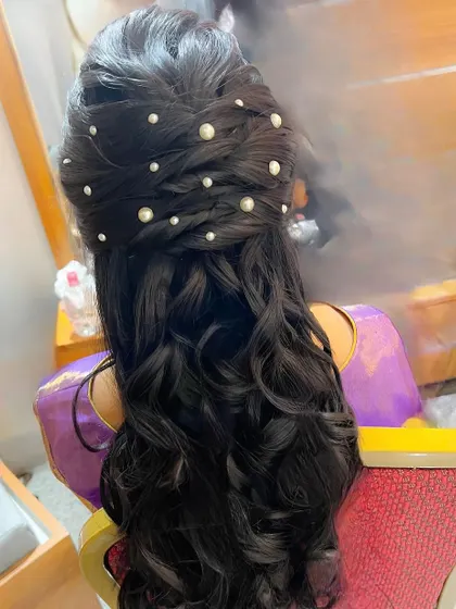 A beautiful half-updo with a braided detail and scattered pearls, perfect for a reception or engagement.