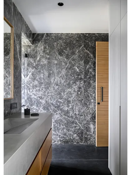 The son's bathroom uses a classic combination of wood, concrete, and white. A custom concrete basin sits atop a warm wood vanity.