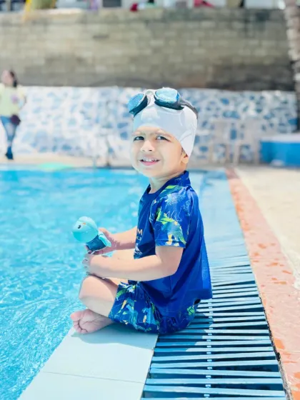 Ready for his lesson, a young boy sits at the edge of the pool. We ensure every child is properly equipped and mentally prepared before entering the water.