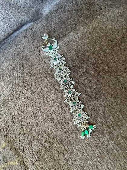 This is a Victorian-style hair accessory (jadanagam) with green stones and pearls. It's perfect for decorating a long braid for a traditional yet modern look.