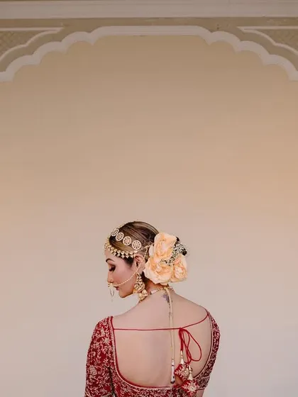 A beautiful shot of the bride's back, showcasing her elegant hairstyle with a floral bun and the intricate design of her blouse.