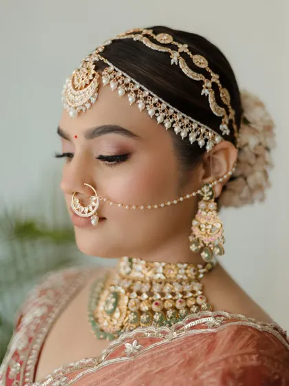 A close-up on bridal beauty. This shot highlights the flawless makeup, the intricate mathapatti, and the bride's calm and collected demeanor.