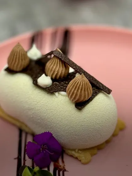 A velvety white dessert, our Mascarpone Chocolate Cheesecake is a study in texture. The smooth, sprayed finish contrasts with the piped chocolate details, creating a modern and elegant look.