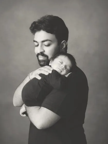 A father holding his sleeping newborn close. These quiet, intimate moments are some of the most powerful memories from the newborn stage.