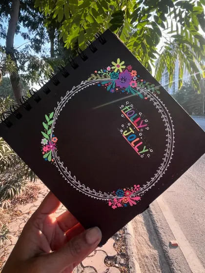 The "Holly Jolly" doodle held up outdoors, with the sun making the colors shine.