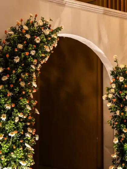A simple yet beautiful floral archway marking the entrance to the event space. The lush arrangement of white roses creates a classic and welcoming first impression for guests.