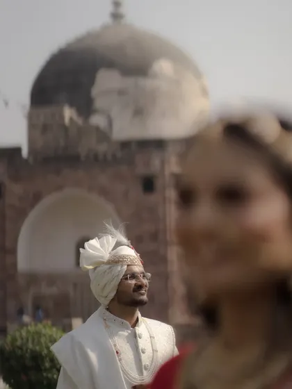 A creative portrait using depth of field, with the groom looking up in the background and the bride's smiling face softly blurred in the foreground.