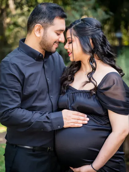 A classic and intimate close-up. This portrait of an expecting couple in matching black outfits highlights their connection and the beauty of the baby bump in a simple, elegant way.