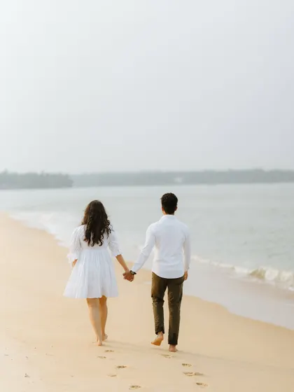 A couple walking hand-in-hand on a beach, a perfect shot for a pre-wedding or destination wedding album.