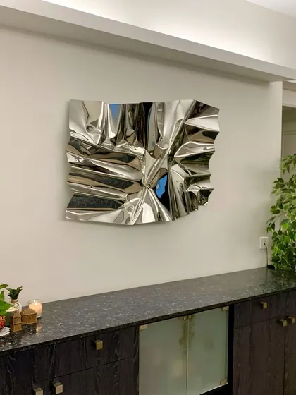 A classic silver Meteor sculpture installed in a client's home, adding a touch of modern sophistication above a dark wood console.