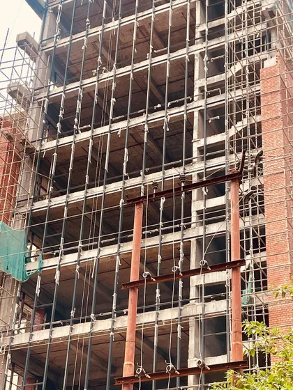 This photo shows the building's raw concrete frame before the brick facade is fully applied. It reveals the structural skeleton that forms the foundation of the final architectural design, highlighting the importance of solid engineering.