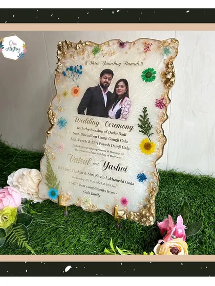 A full view of the resin wedding invitation, displayed on a stand and surrounded by flowers.