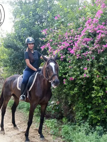 A rider poses with her horse next to a blooming bougainvillea bush. Our trails are full of beautiful flora, adding vibrant color to your riding experience.