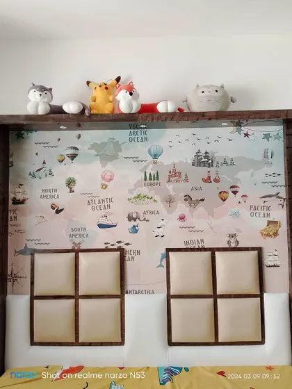 A children's world map wallpaper installed behind a bed, serving as a creative and educational headboard.