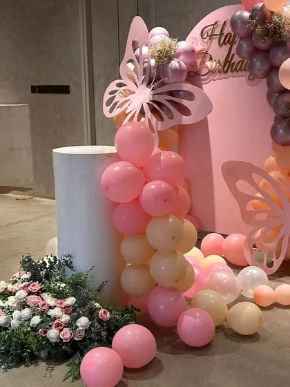 We added a lush floral arrangement at the base of the cake plinth to bring a touch of nature into this whimsical butterfly theme. The soft pinks and whites of the flowers complement the balloon colors perfectly.