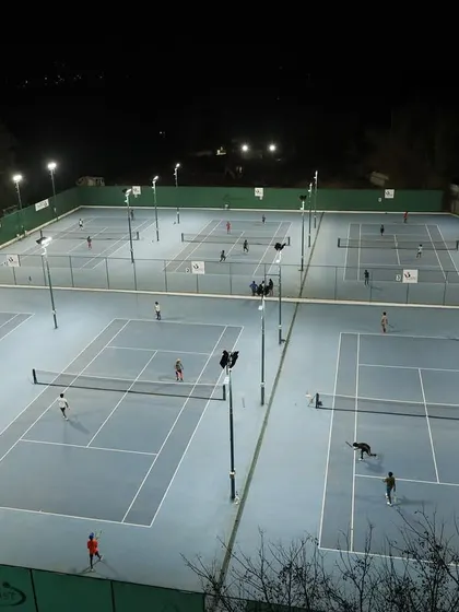 An aerial view of our courts illuminated at night. Our state-of-the-art floodlights allow for extensive practice sessions after sunset, ensuring every player gets the court time they need to improve.