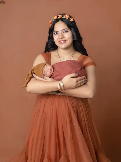 A beautiful portrait of a mother holding her newborn. The floral headband adds a lovely, soft touch.