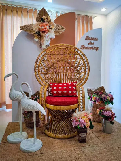A boho-chic baby shower with a "Babies Are Brewing" sign. The peacock chair, flamingo props, and dried florals create a relaxed and stylish vibe.