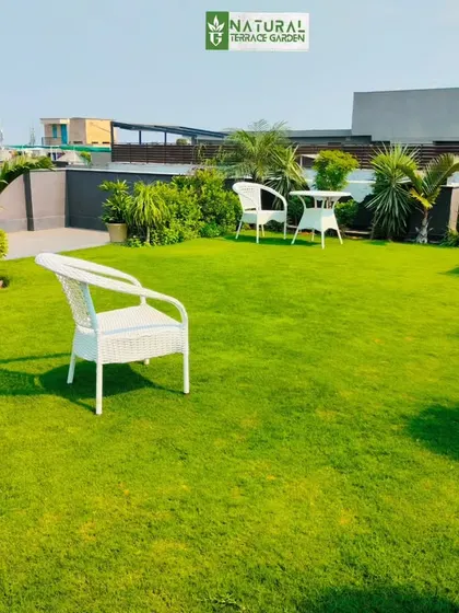 A simple and elegant rooftop lawn with white wicker furniture, offering a clean and open space for relaxation.