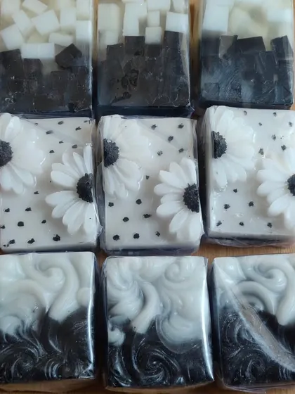 A collection of black and white themed soaps, showing different artistic techniques from swirls to floral appliques.
